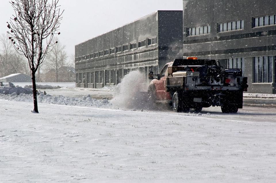 Commercial plow truck clearing an office property during active snowfall